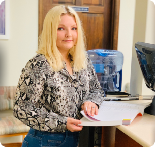 A woman wearing a black shirt and jeans stands at a counter, looking engaged in conversation.