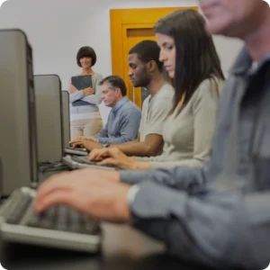 A diverse group of individuals focused on their work at computers in a modern office setting.