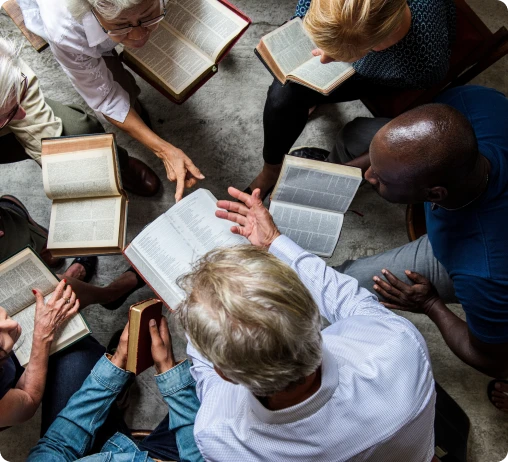 A diverse group of people engaged in discussion while sitting around a table filled with books.