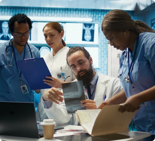 A group of doctors gathered around a laptop, discussing information displayed on the screen.